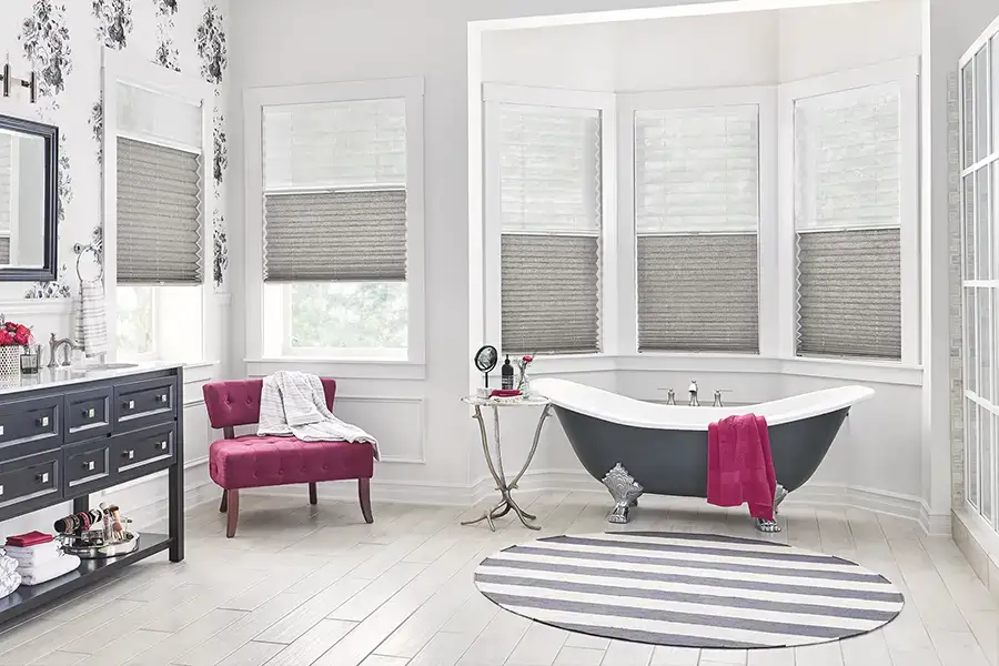 Add a pop of color to your bay window with cellular shades. Dark gray cellular shades within a bay window area inside a modern like bathroom