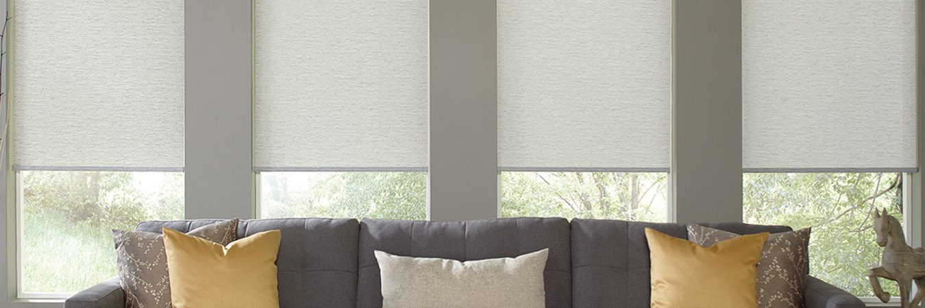 Light gray motorized shades above a long dark gray couch