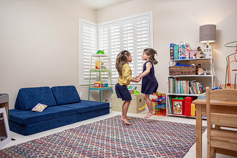 Kids playing in a play room with white polywood shutter windows in the corner