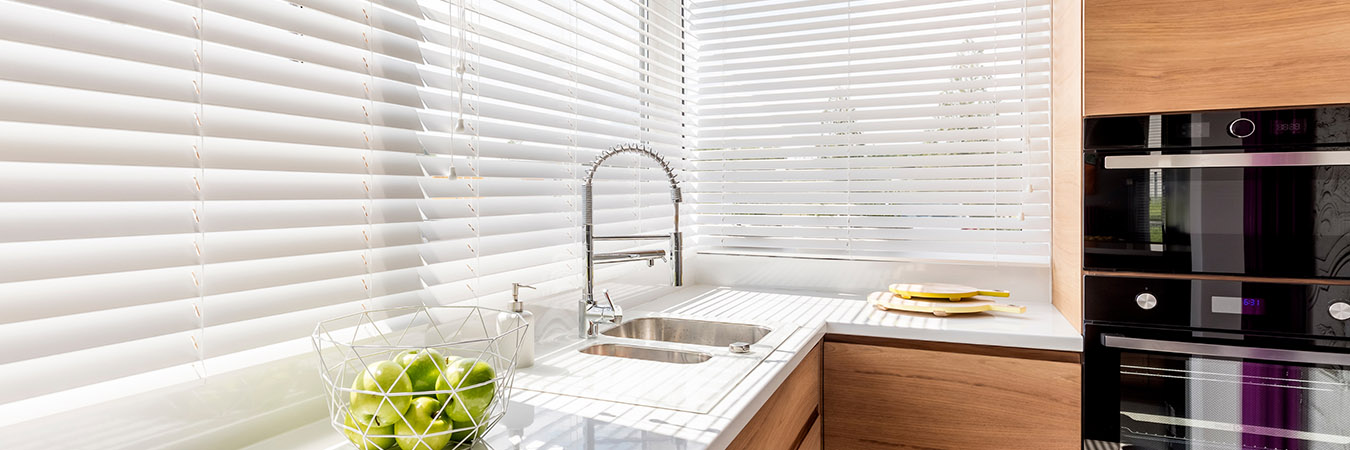 White window blinds in a kitchen with wood finishes