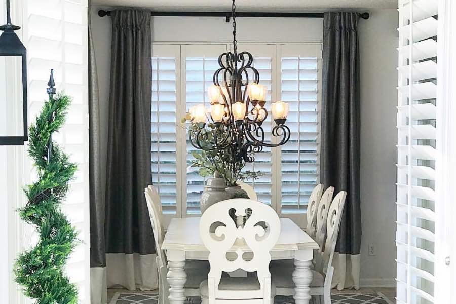 Dark gray curtains framing white Polywood curtains in a light gray dining room