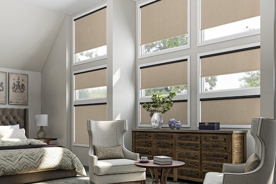 Beige roller shades on several windows in a bedroom