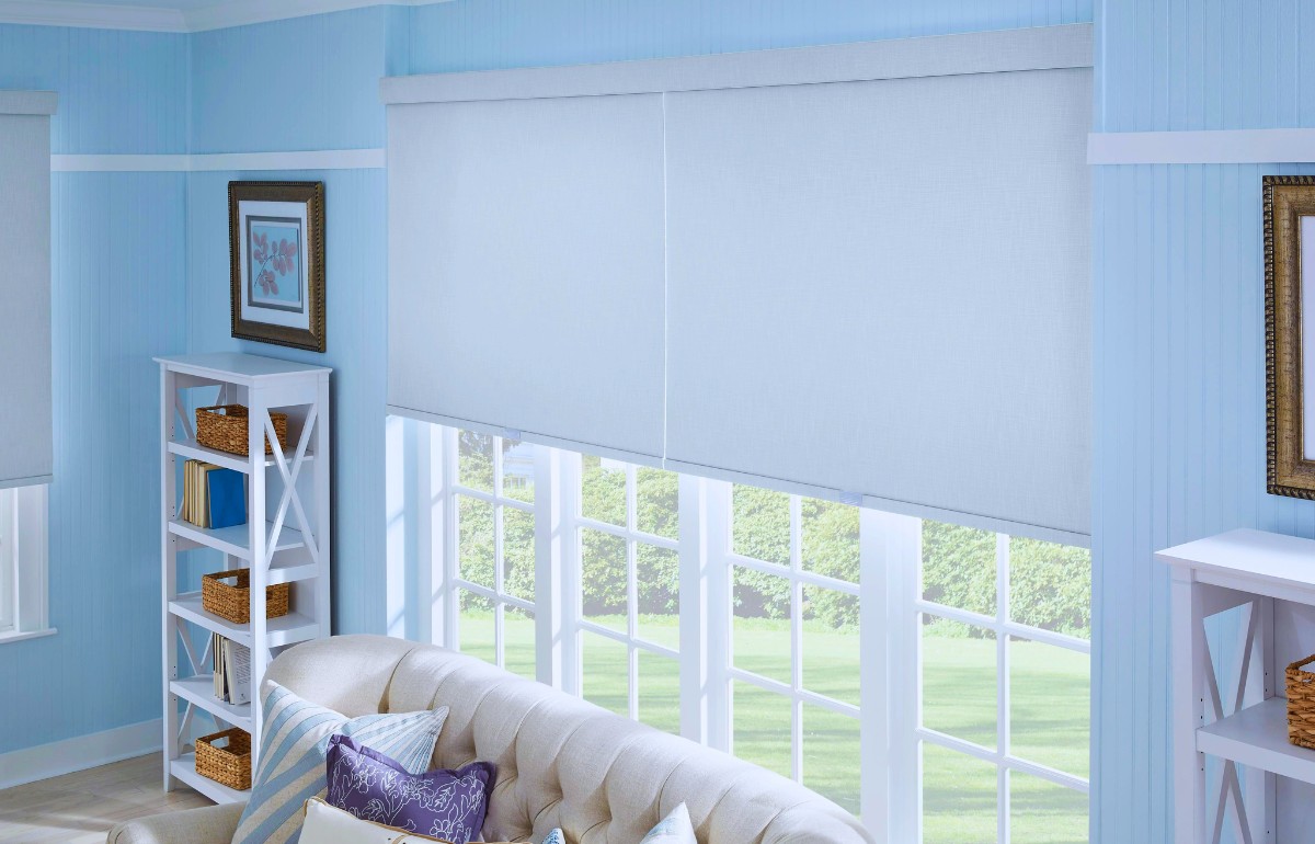 Large white roller shades on living room windows