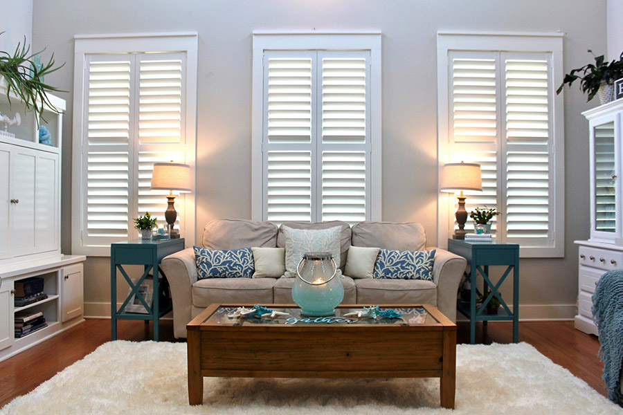 White Polywood shutters with divider rails and hidden tilt rods on living room windows