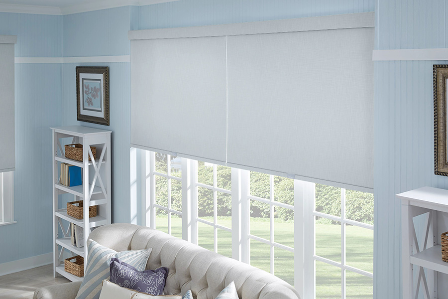 Large white window shades on tall windows behind a sofa