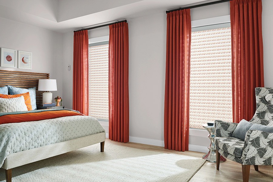 Orange and white patterned cellular shades on bedroom windows