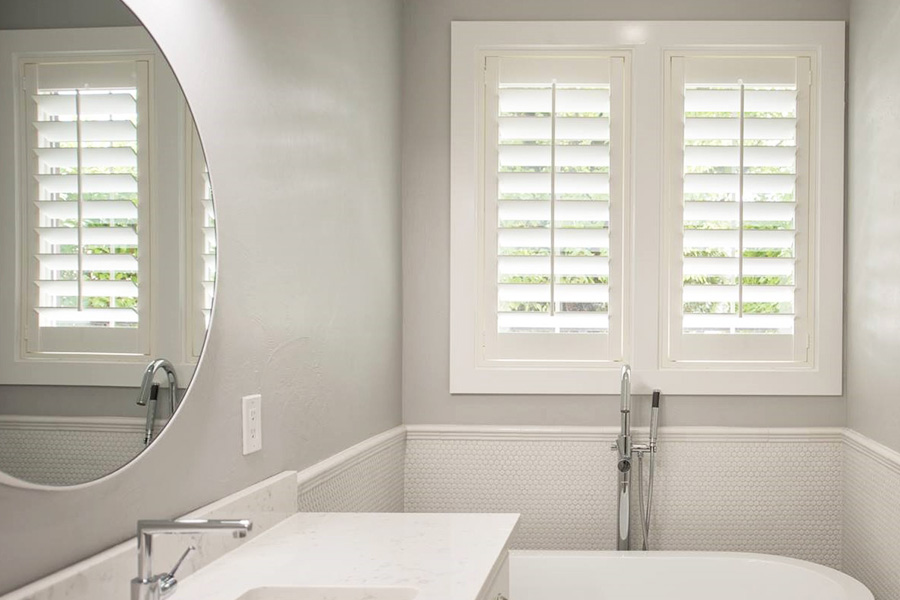 Polywood shutters on a window in a white bathroom