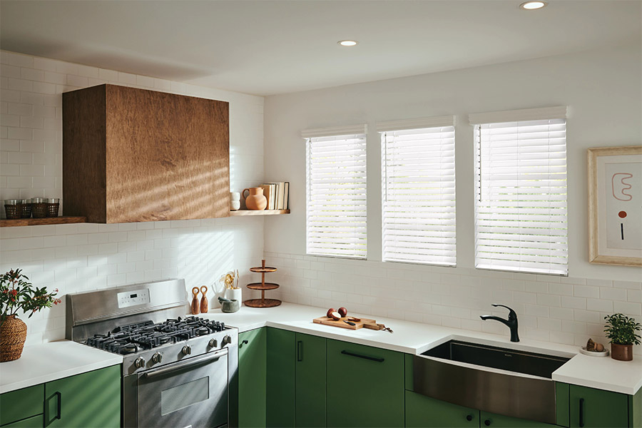 white blinds above a kitchen sink with green cabinets