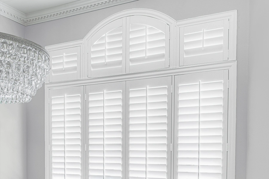 Putting in a specialty-shaped window? Add a custom interior shutter too! White Polywood shutters on a Palladian window in a white dining room