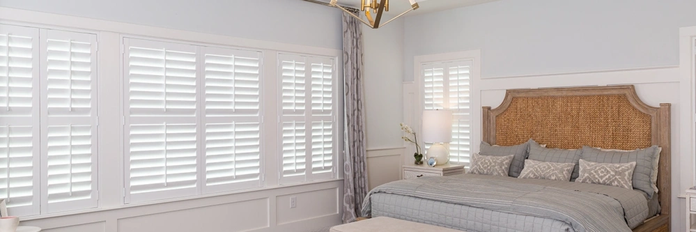 Closed white polywood shutters inside a large bedroom