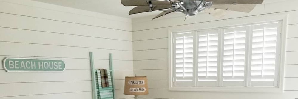 White polywood shutters on a large basement level window.