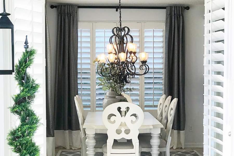 Get all the privacy and light control you want when you pair versatile plantation shutters with stylish curtains. Dark gray curtains framing white Polywood curtains in a light gray dining room