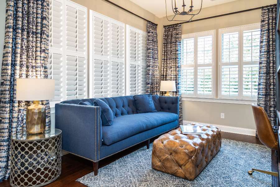 Colored or patterned drapes look lovely when paired with neutral interior shutters. Blue patterned drapes paired with white Polywood shutters in a living room