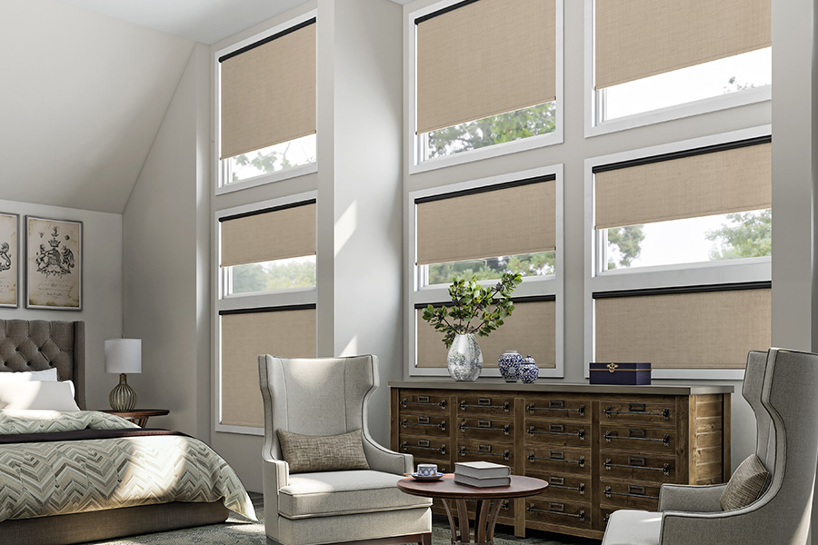 Put motorized shades on unreachable windows and open or close them with a button. Beige roller shades on several windows in a bedroom
