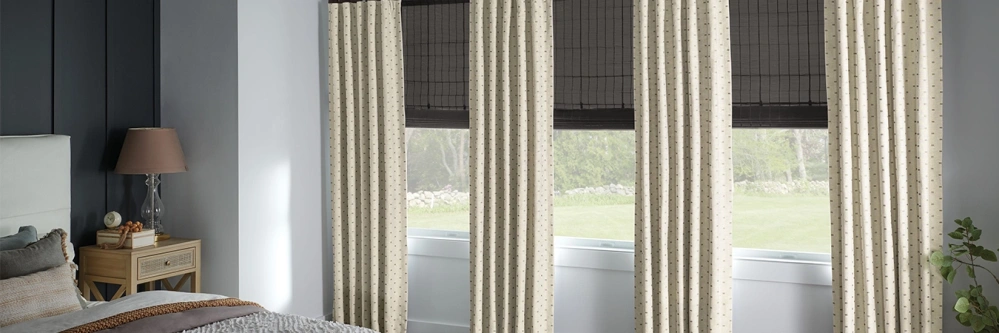 Gray window shades and cream drapes on bedroom windows