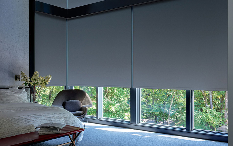 Our professionals will install your motorized shades for optimal performance--on your schedule, when you're ready. dark roller shades in a large modern bedroom