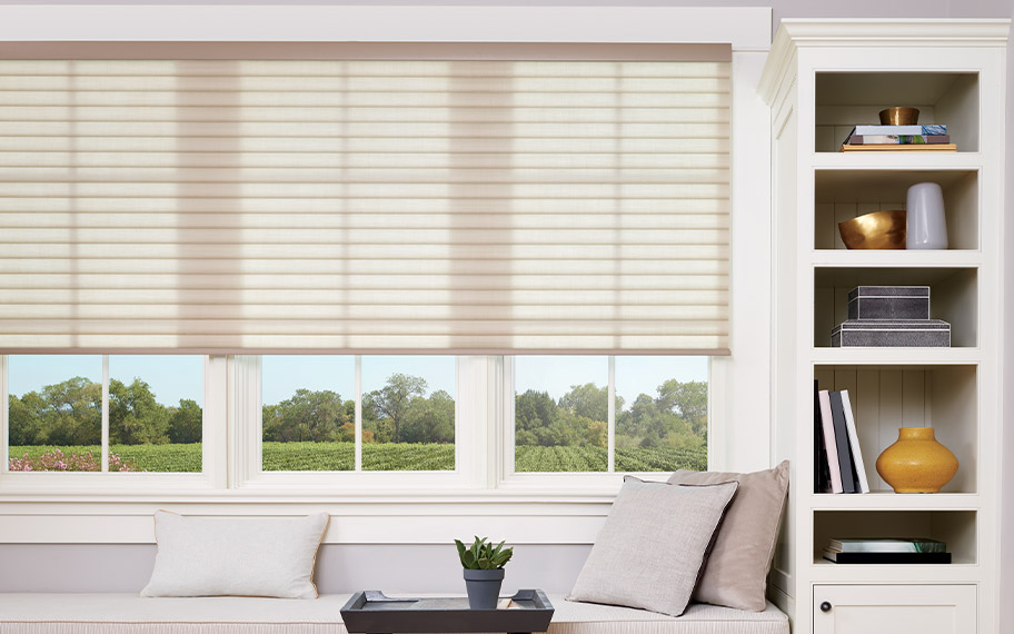 Choose your own style of modern motorized shades. Beige cellular shades above a window seat