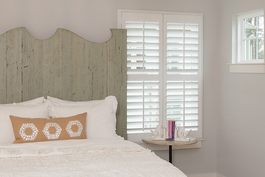 Blinds and shutters are both stunning ways to upgrade your home. Bedroom with white Polywood shutters.