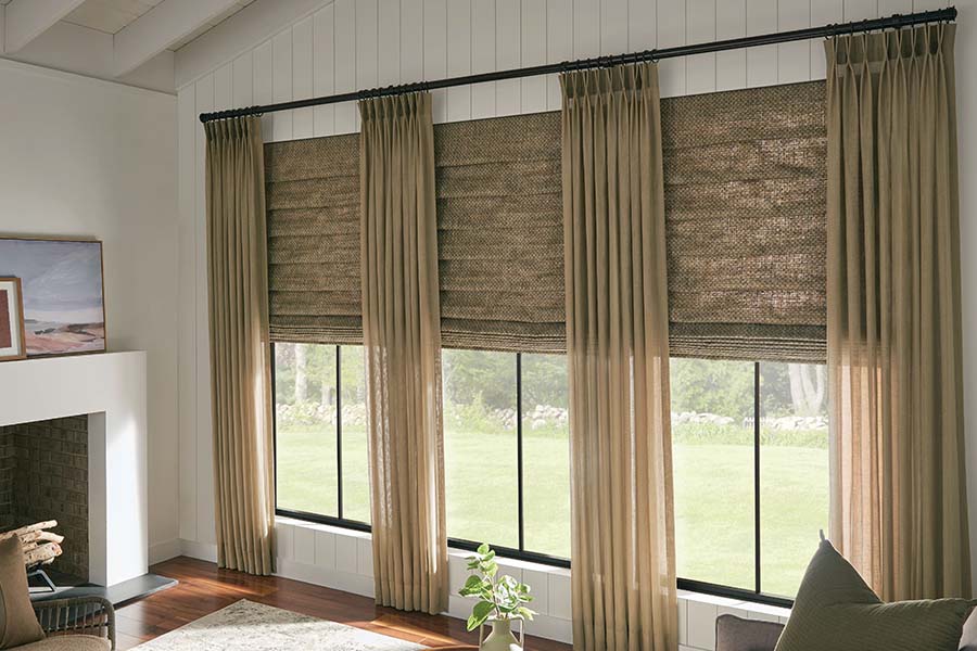 Combining window shades and curtains lets you play with colors and textures on your windows. Matching Roman shades and curtains on living room windows