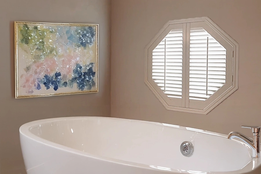 Bathroom with white shutter window treatments including an octagon white shutter window above the tub