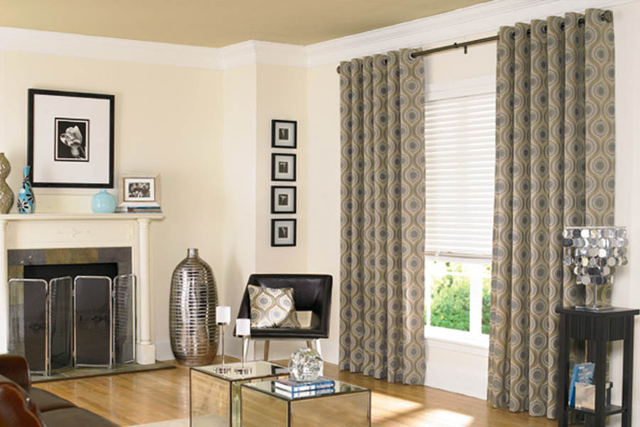 Curtains and sturdy blinds are a classic look for any window. Sage green patterned curtains on white blinds in a living room