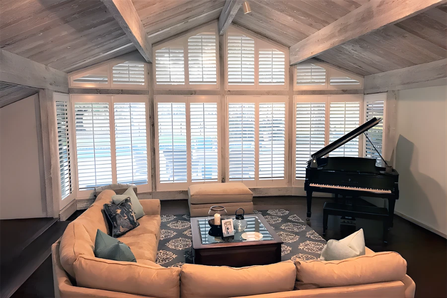 Solid interior shutters give you the most insulation against temperature transfer on large rake windows. Interior shutters on a wall-length rake window