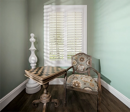 white polywood shutters within a small nook with a chess piece decor and chess board and table with a chair