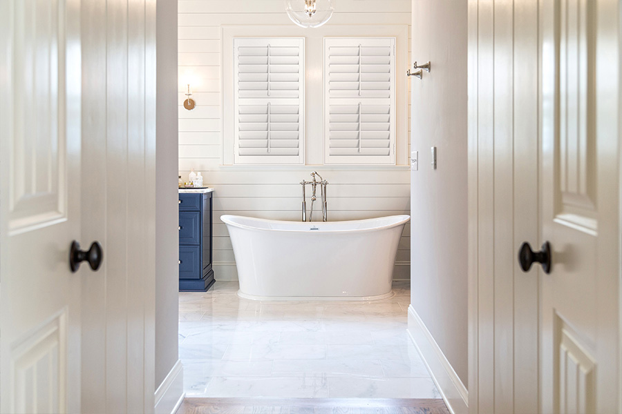 Even in humid bathrooms, durable Polywood shutters look beautiful for decades. White Polywood shutters on windows over a white bathtub