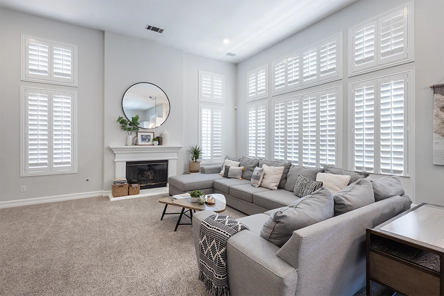 Polywood shutters on tall windows in a white living room