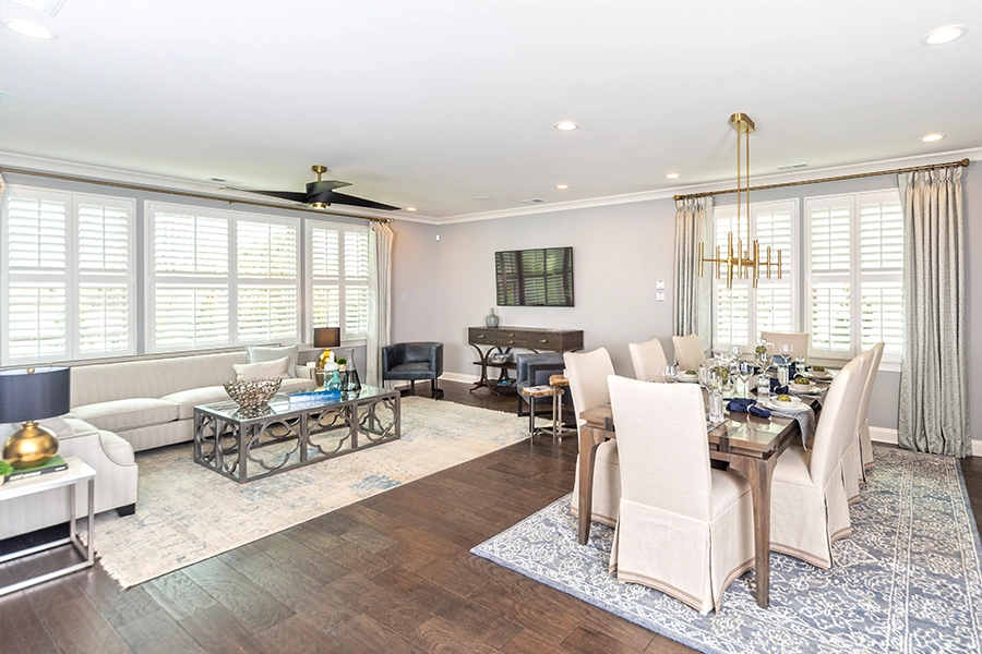 Using the same kind of window treatment on windows in a shared space ties everything together. Polywood shutters and drapery on windows in a living room/dining room